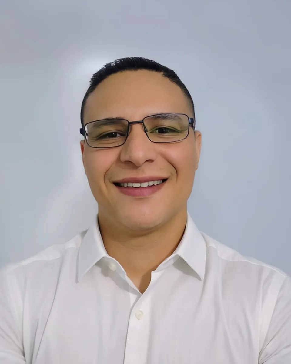 José Alejandro Valverde Briceño, con camisa blanca y anteojos, sonriendo
